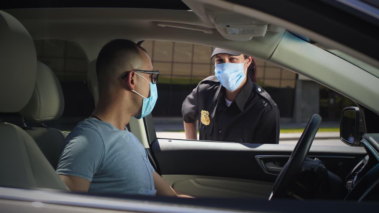 male Police Officer in Green Uniform with Notepad Checking Vehicle with Girl Driver Inside Male Police Officer in Green Uniform with Notepad Checking Vehicle with Girl Driver Inside