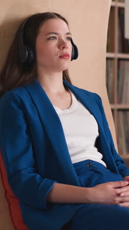 woman enjoys film on library hanging tv using headphones. lady utilizes digital technology to watch film in college library. device for personal viewing experience