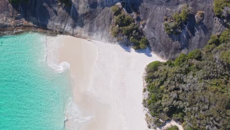 top down drone shot of water lapping against the white sand on misery beach in albany, western australia