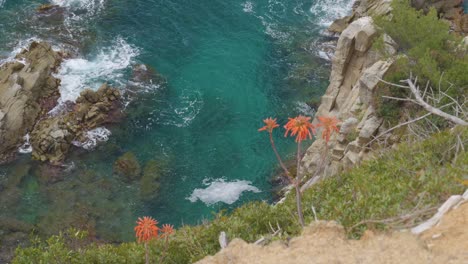 View-of-the-ravine-precipice-with-drop-to-the-Mediterranean-turquoise-blue-sea-with-green-vegetation-rocks-in-the-water-calm-water