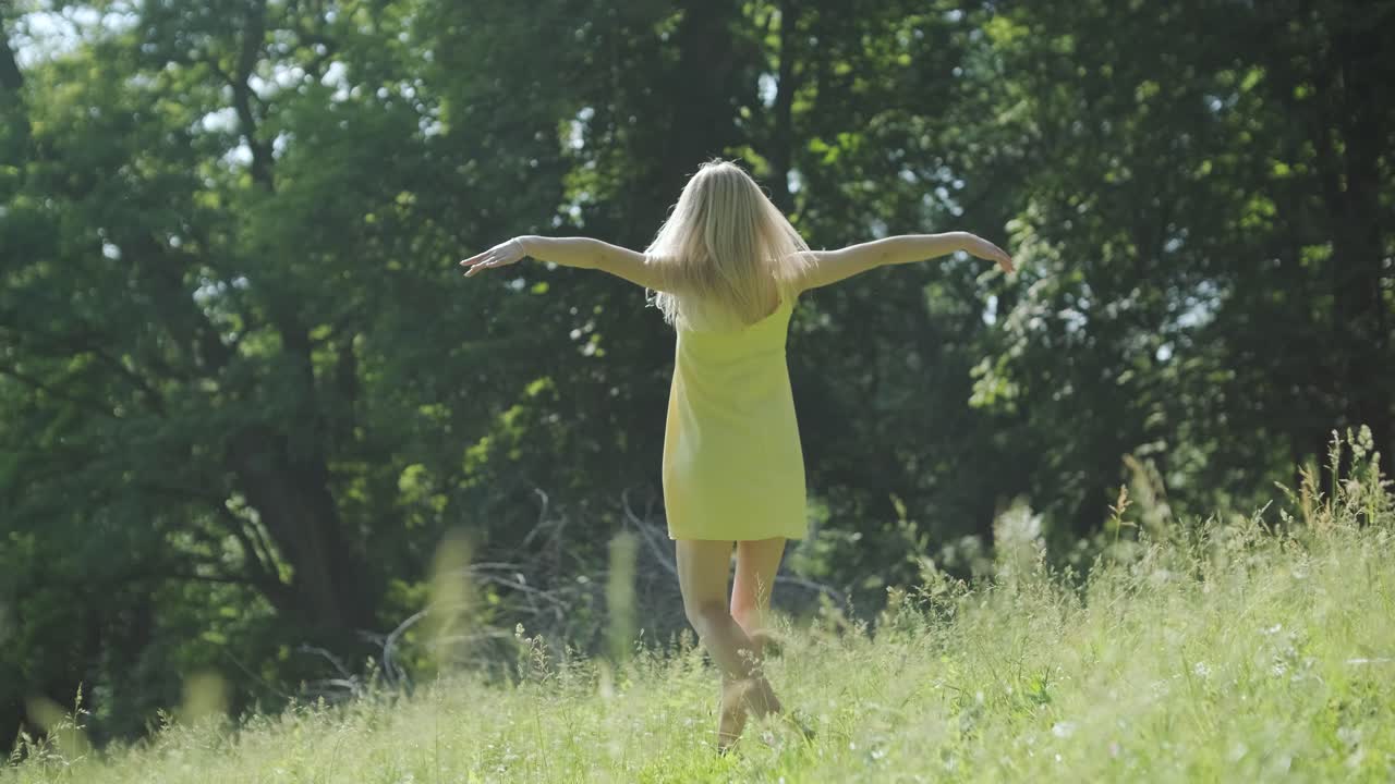 mujer con vestido amarillo bailando con gracia en el parque de verano