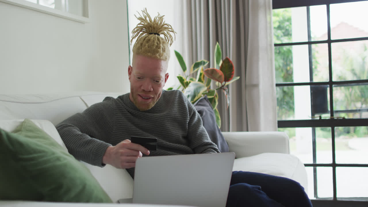 Albino african american man with dreadlocks using laptop