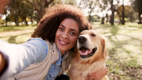 woman taking a selfie with her golden retriever in the park