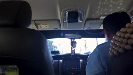 experience a unique perspective from the backseat of a taxi cab in thailand. captured is the driver navigating through tropical landscapes, creating a feeling of adventure and exploration.