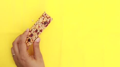 hand holding a granola bar on a yellow background