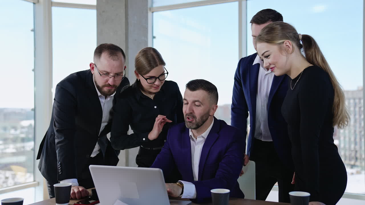 Diverse office team employees gathered around their boss. Colleagues discuss issues on director laptop. Blurred backdrop.