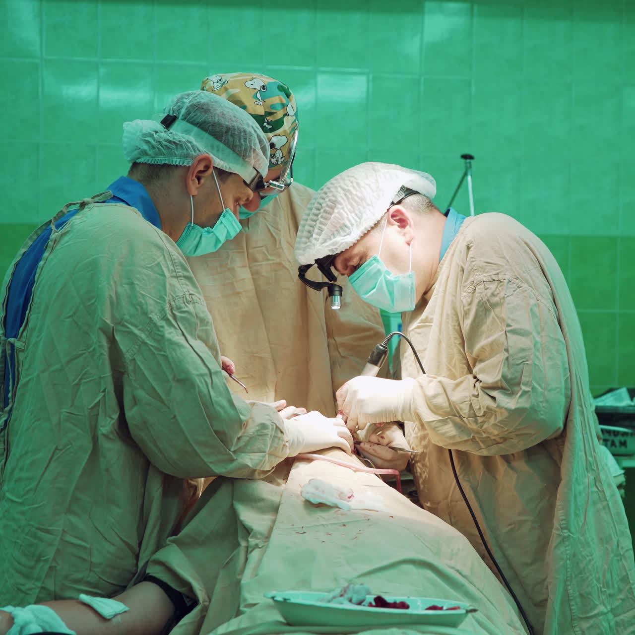 Professional doctors wearing protective clothing performing surgery using sterilized equipment. Medical team performs surgical operation in a big operating room in hospital.