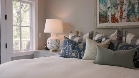 Bedside-nightstand-with-lamp,-white-bedding,-and-colorful-pillows