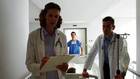 médicos discutiendo sobre el informe médico mientras empujan la cama de camilla de emergencia