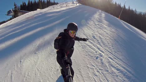 front view of a snowboarder going down through people with a selfie stick on a clear day