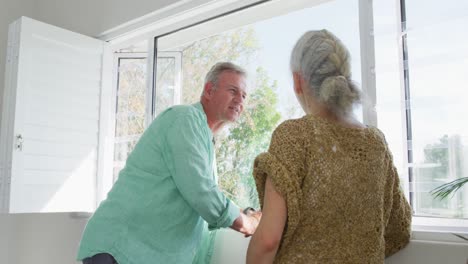 Happy-caucasian-senior-couple-standing-at-window