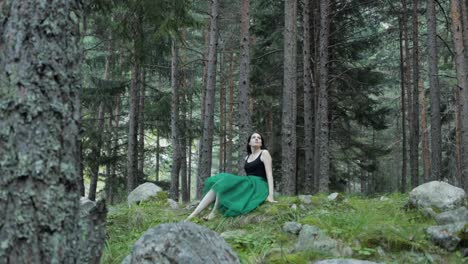 free spirit female wearing green skirt laying on grass in forest wilderness before getting up and walking away