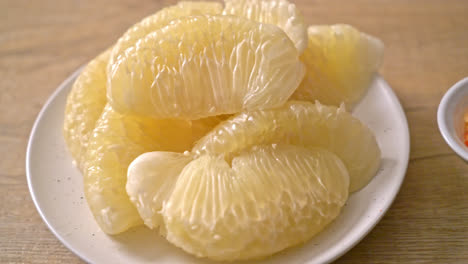 fresh peeled pomelo, grapefruit or shaddock on white plate