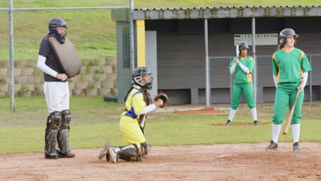 multiracial female baseball players and male umpire, catching and throwing the ball on a pitch