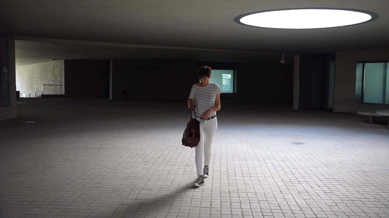 A stylish woman gracefully walking through a modern architectural space of distinction