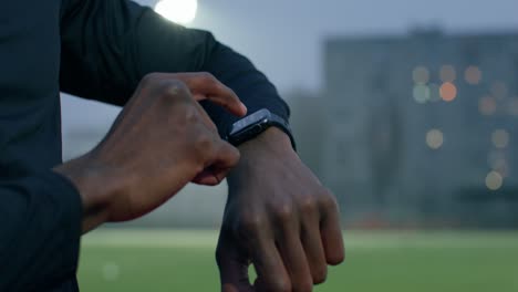 athlete checking smartwatch at night on a sports field