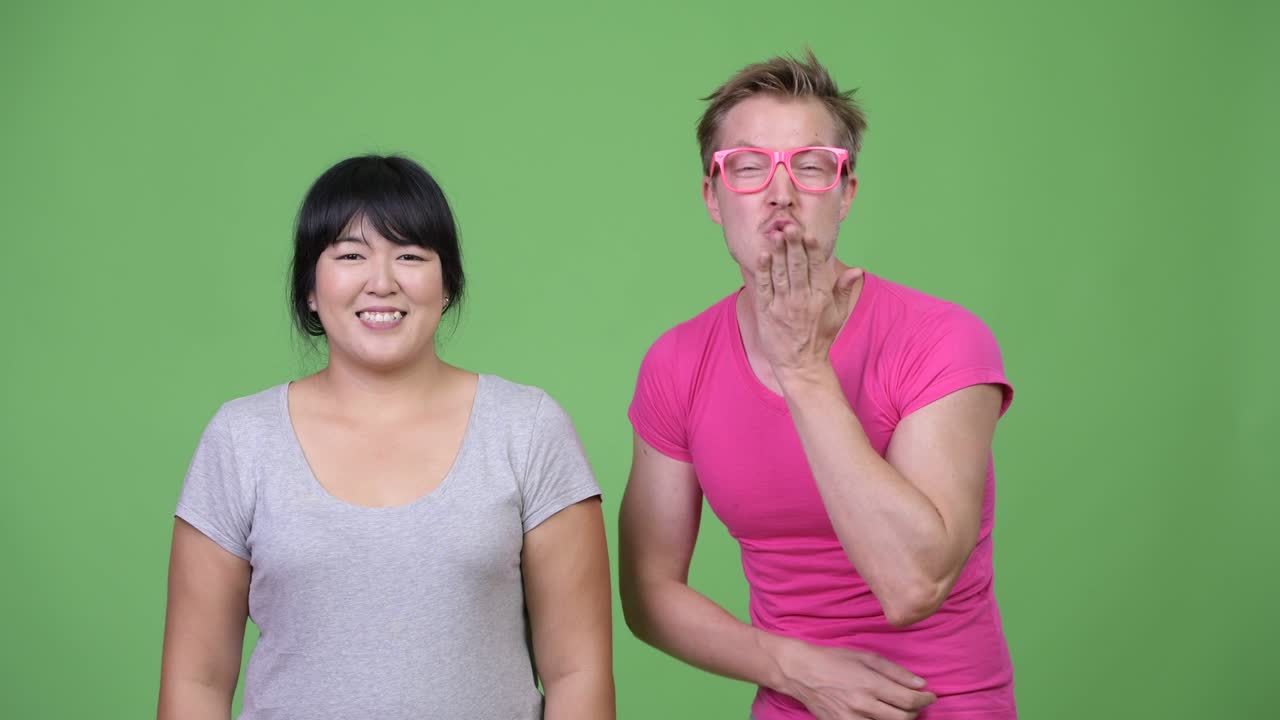 Happy overweight Asian woman and young gay man smiling together