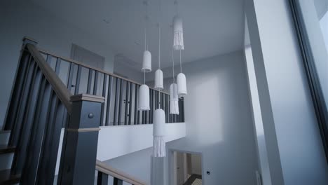 an elegant staircase with classic wood balustrades and unique white pendant lights creates a modern yet timeless atmosphere within a high-ceilinged home space