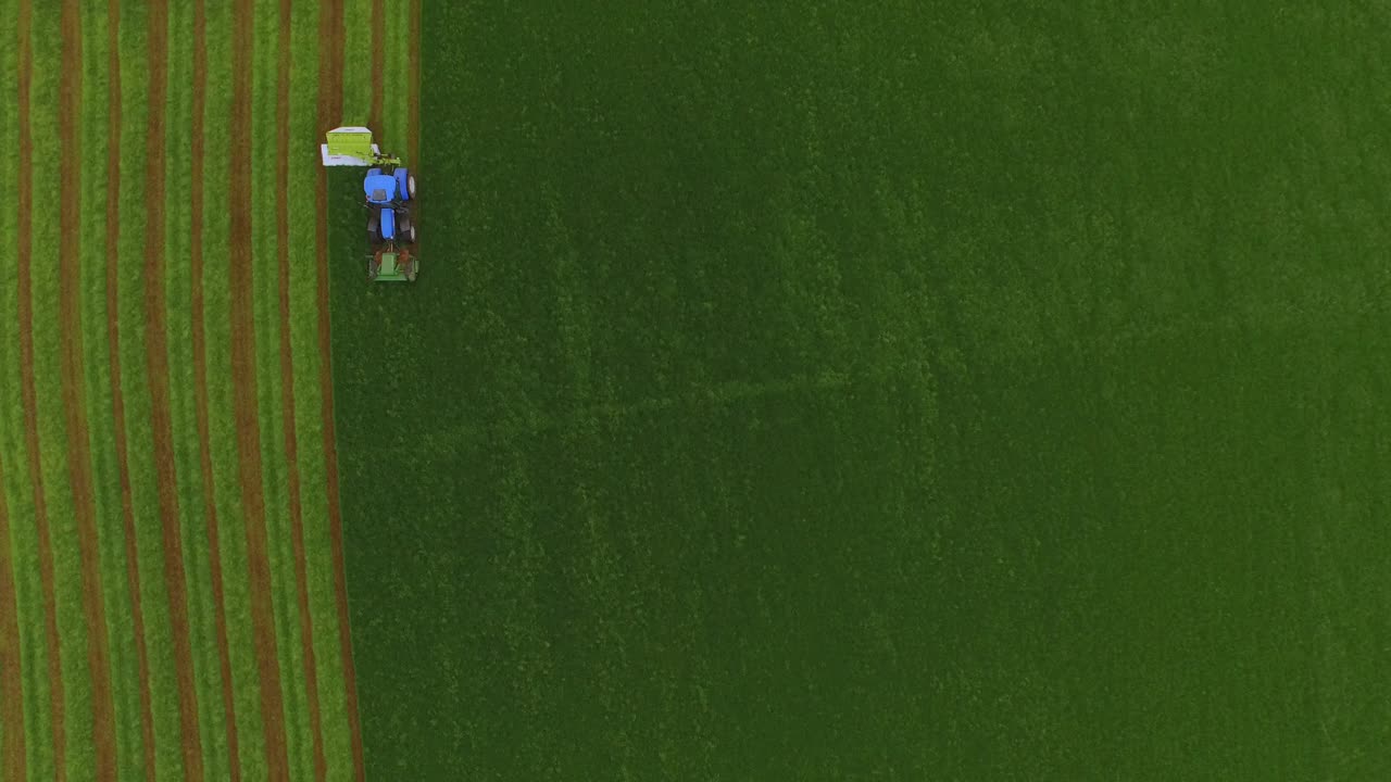 vista aérea de un tractor cortando la hierba en un gran campo verde