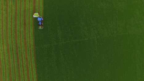 vista aérea de un tractor cortando la hierba en un gran campo verde