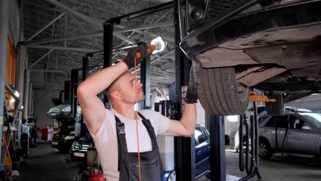 Mechanic inspecting car undercarriage in an auto repair garage