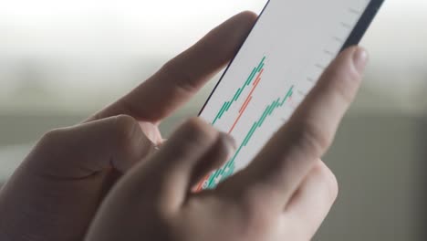 Looking-at-the-stock-market,-stocks,-investment-charts-on-the-phone,-close-up.