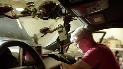 view from inside car of male workshop technician busy removing windshield