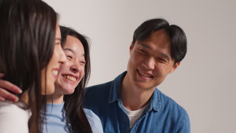 side view of group of young friends in front of white studio background posing for photo booth style portraits 2