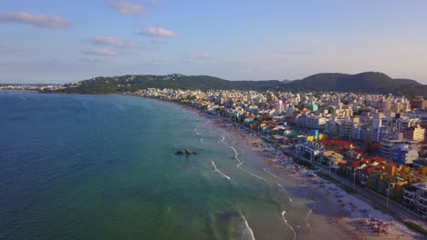 plano general aéreo de la playa de bombas llena de turistas a la hora dorada, brasil