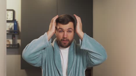 portrait of a tired young man in a bathrobe according to a hangover and head underwear