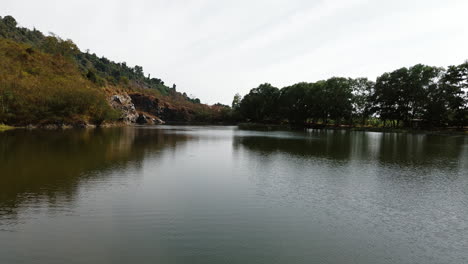 a calm lake surrounded by green trees, captured in tay ninh, south vietnam