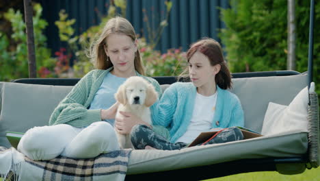 two girls playing with a puppy, sitting on a swing in the backyard of the house