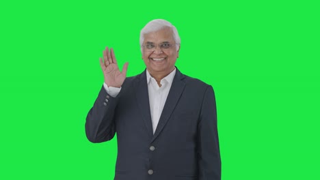 Happy-Indian-senior-journalist-saying-Hello-and-waving-hand-Green-screen