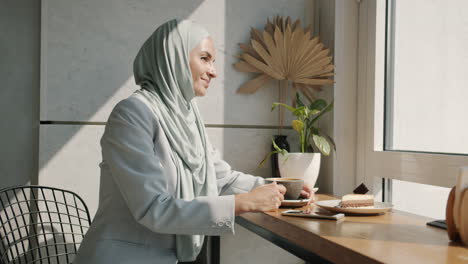businesswoman enjoying coffee and cake at cafe window