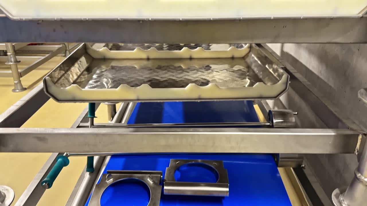 Industrial interior of Latvia wastewater treatment facility showing stainless steel trays, custom blue cutting boards with metal fixtures, roller conveyors in processing area