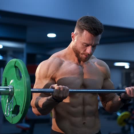 handsome male athlete with perfect body trains with barbell in gym. strong body and perfect abs. slow motion