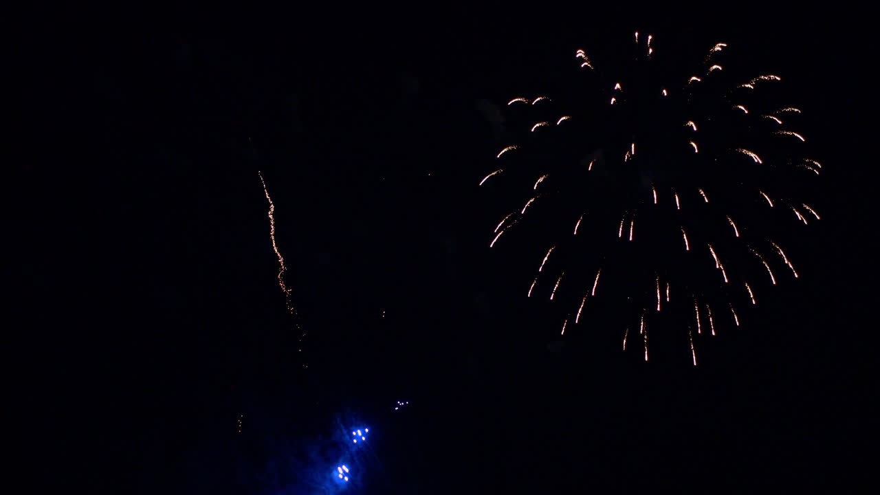 Long thin lines of light burst into explosions of colorful fireworks
