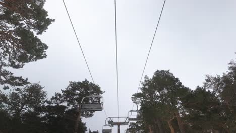 view from below of the ski-lift chairlift in winter against cloudy sky in madrid mountains