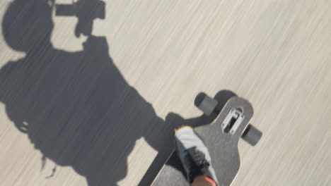 person riding electric skateboard on the road on a sunny day, shadow