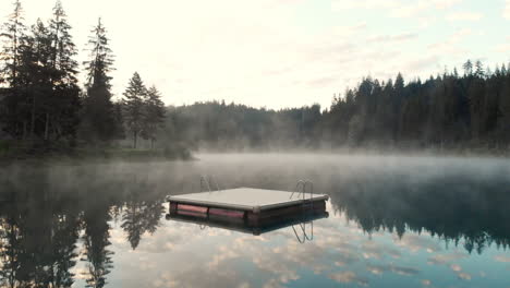 panoramic view forest and beautiful reflection of sky and trees in caumasee lake on a foggy day - drone shot