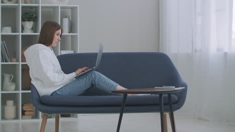 Woman-using-laptop-on-couch-at-home.-Thoughtful-young-woman-sitting-with-computer-on-couch-looking-outside-concentrate-on-work-feeling-bored-need-additional-motivation-working-remotely-at-home.