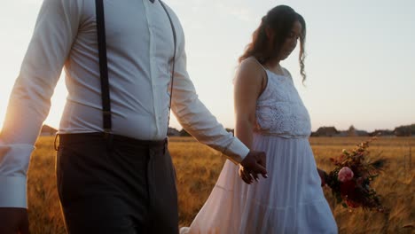 pareja caminando de la mano en un campo de trigo al atardecer