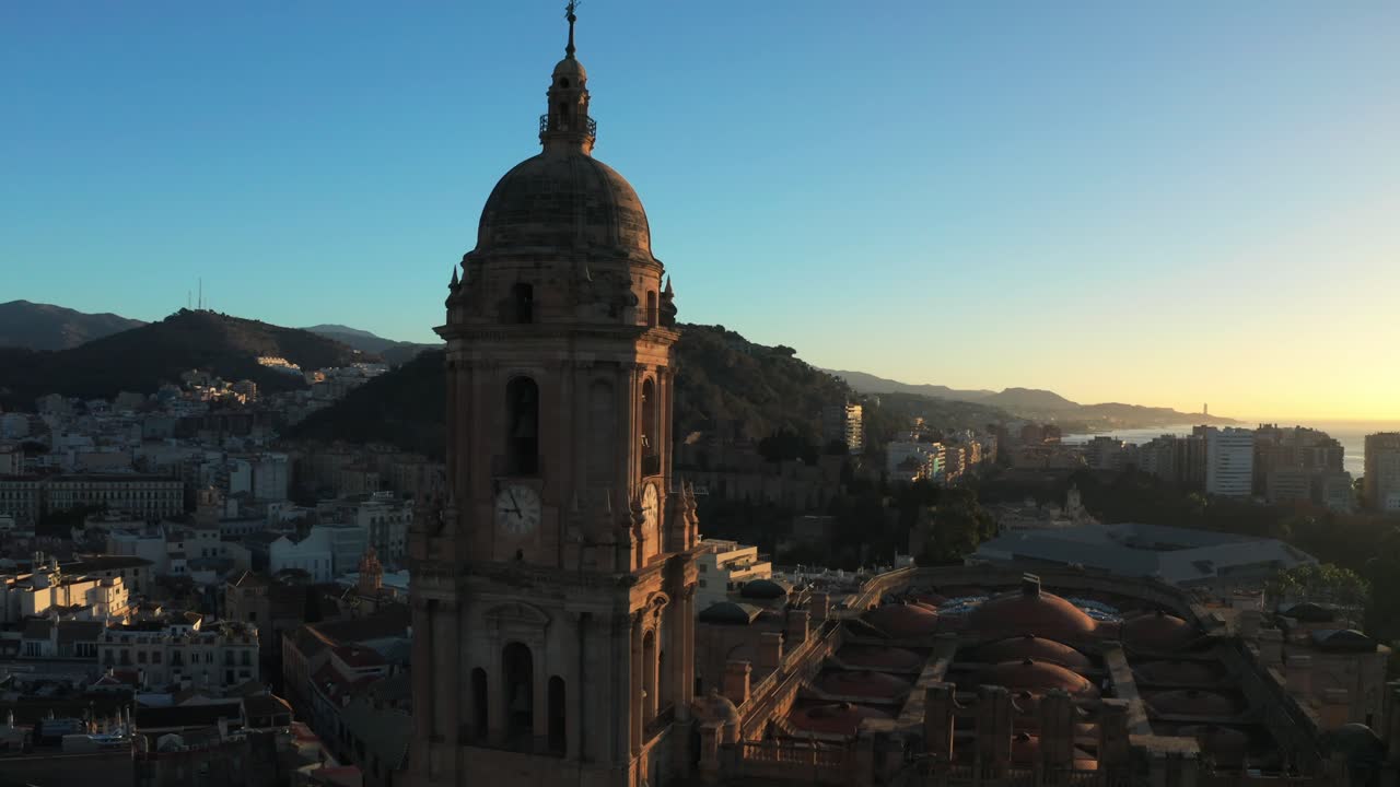 dron sobre el campanario de la catedral de málaga contra el brillante sol amarillo que brilla sobre la ciudad y el puerto de andalucía, españa
