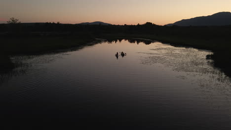 people kayaking at the calm cherry river at sunset in magog, quebec, canada