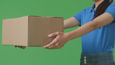 close up of a female courier in blue uniform giving a carton to someone while delivering it on green screen background in the studio