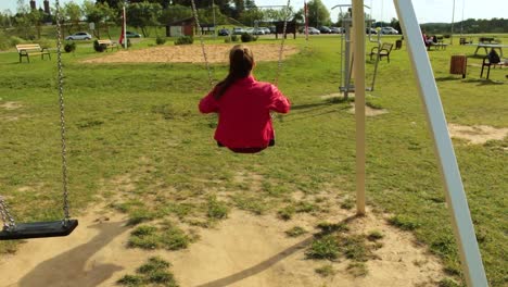 Girl-with-red-jacket-swinging-on-the-swing-set