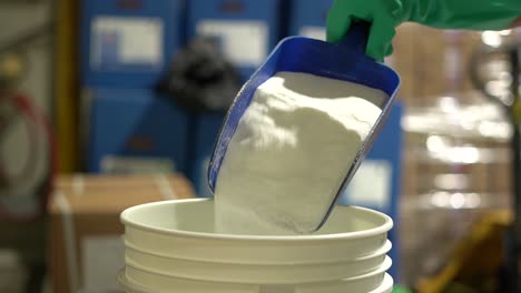 fishery industry: a worker pouring fish processing additives into a bucket, slow motion handheld shot