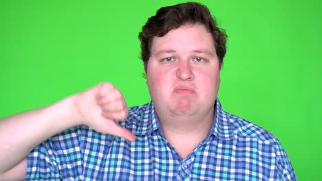 man giving thumbs down sign signifying rejection, refusal, or disapproval on green screen.