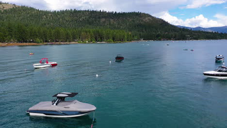 drone disparado sobre barcos amarrados que se elevan hacia la orilla del lago tahoe, en los soleados estados unidos