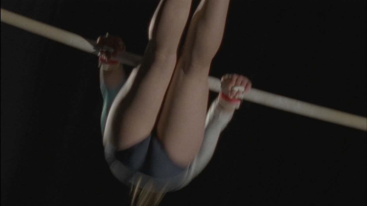 A woman performs a gymnastic routine on bars